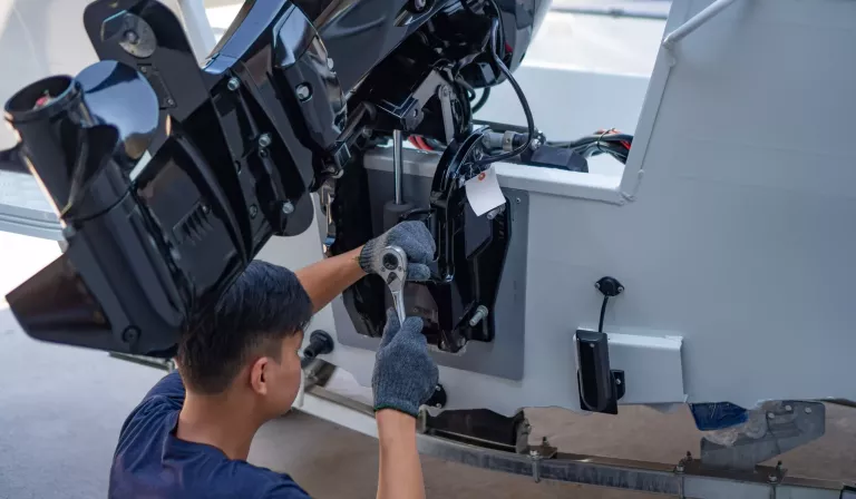 Mechanic is installing speed boat engine , a new engine on an aluminum boat.